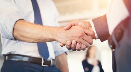 Businessmen shaking hands during a meeting. Closeup of business handshake between two colleagues in a modern office. Successful businessmen handshaking closing a deal. Agreement and business concept.